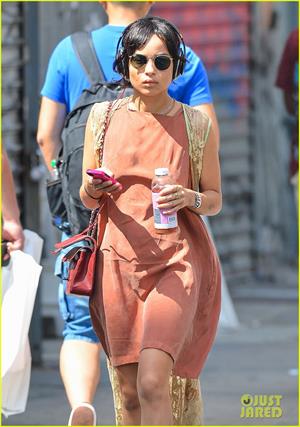 Zoe Kravitz walking in shorts and an orange top