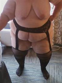 Just me wearing a garter belt and stockings and showing my big, natural, 48DD tits. This picture of me was taken in a hotel in front of an open window. It was a real turn on, knowing that people walking by could look right in and see me posing.