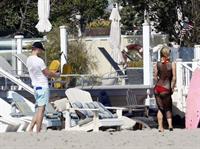 Paris Hilton at the beach in a skimpy red bikini and fishnet kaftan in Malibu.July 12, 2013