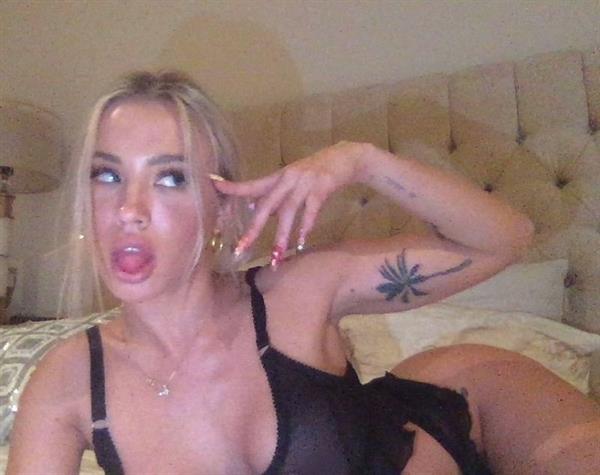 Tammy Hembrow boobs in see through lingerie showing off her big tits laying in bed in matching black bra and panties.